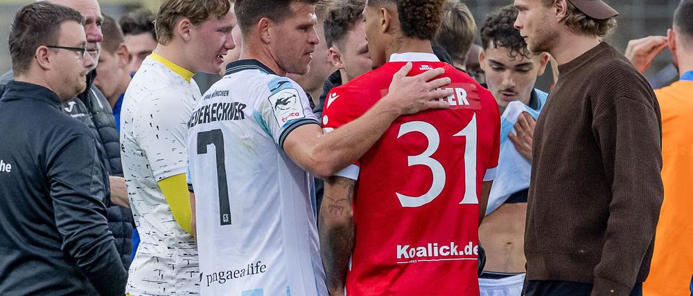 Florian Niederlechner (TSV 1860 München) spricht nach dem Rassismus-Vorfall aufmunternd mit Justin Butler (FC Energie Cottbus).