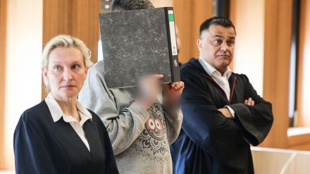 Der angeklagte Krankenpfleger hält sich zwischen seinen Anwälten Volker Breyer (r.) und Tanja Tomasso (l.) einen Aktenordner vor das Gesicht. Der Krankenpfleger steht wegen Mordes an neun Patienten vor dem Aachener Landgericht.