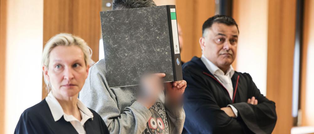 Der angeklagte Krankenpfleger hält sich zwischen seinen Anwälten Volker Breyer (r.) und Tanja Tomasso (l.) einen Aktenordner vor das Gesicht. Der Krankenpfleger steht wegen Mordes an neun Patienten vor dem Aachener Landgericht.