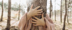 Girl hugging tree trunk in forest
