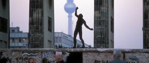 Eine Person tanzt auf der Mauer am Brandenburger Tor.