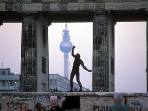 Eine Person tanzt auf der Mauer am Brandenburger Tor.