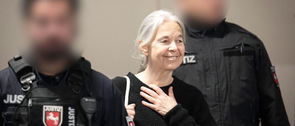 Die Angeklagte Daniela Klette reagiert zu Beginn des Verhandlungstages auf Unterstützer im Zuschauerbereich des provisorischen Gerichtssaals des Landgerichts Verden in Verden-Eitze. 