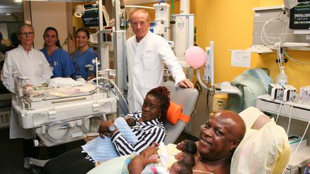 Credit: Berliner CharitéInfo 1: Vorne v. l.: Prof. Wolfgang Henrich, Direktor der Klinik für Geburtsmedizin, die Eltern mit vier Kindern. Hinten v. l.: Neonatologin Dr. Monika Berns, Gesundheits- und Kinderkrankenpflegerin Jessica Blauert und Jasmin Barthel, Studentin der Hebammenwissenschaften. Kind Nummer fünf liegt im Inkubator.