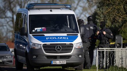 Polizeibeamte stehen bei einer Hausdurchsuchung vor einem Wohnhaus in Reimershagen.
