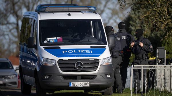 Polizeibeamte stehen bei einer Hausdurchsuchung vor einem Wohnhaus in Reimershagen.