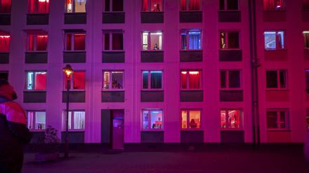 Freier vor der Fassade eines rot beleuchteten Bordells mit Prostituierten in den Fenstern in Düsseldorf.