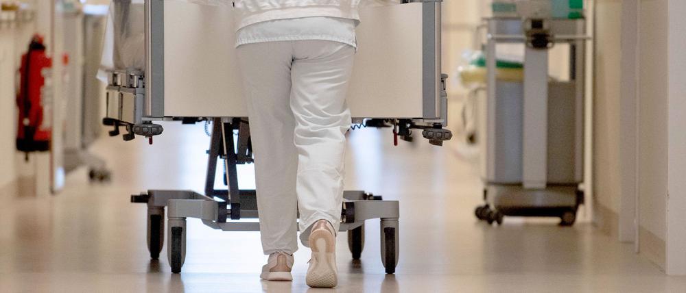 Eine Krankenpflegerin schiebt ein Krankenbett durch einen Krankenhausflur.