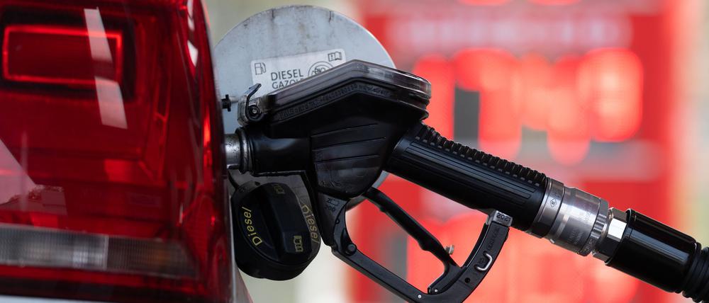 Ein Tankstutzen steckt an einer Tankstelle in der Tanköffnung eines Fahrzeugs.