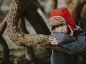 Ein kleiner Junge steht allein an einem Baum.