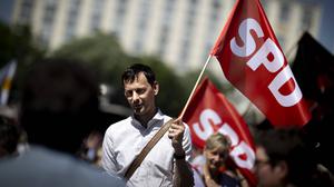 Martin Hikel weht am 1. Mai 2024 bei einer Gewerkschaftsdemo mit einer Fahnde der SPD.