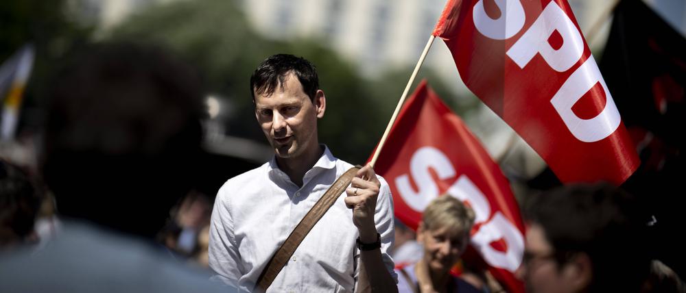 Martin Hikel weht am 1. Mai 2024 bei einer Gewerkschaftsdemo mit einer Fahnde der SPD.