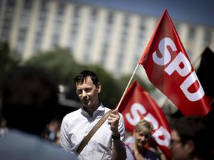 Martin Hikel weht am 1. Mai 2024 bei einer Gewerkschaftsdemo mit einer Fahnde der SPD.