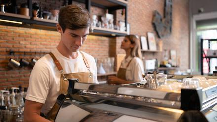 Ein junger Mann arbeitet als Barista in einem Café.  