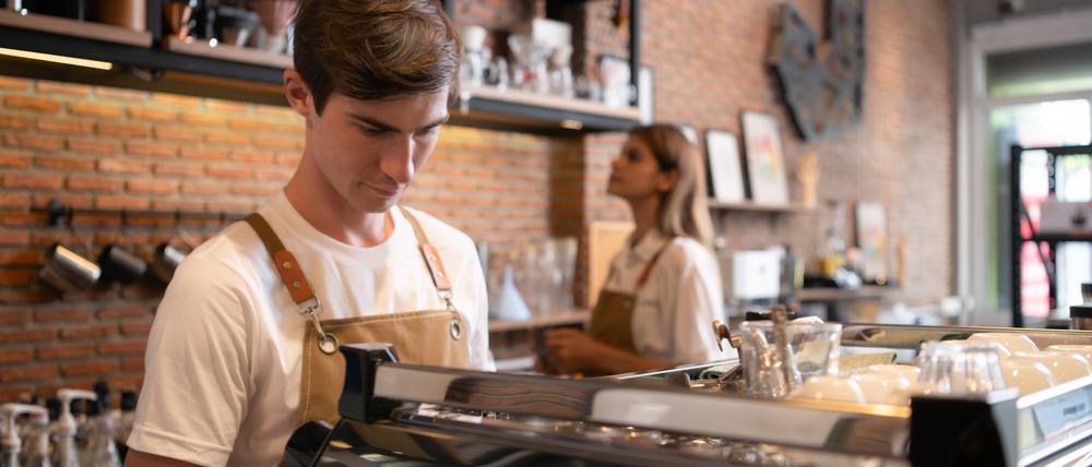 Ein junger Mann arbeitet als Barista in einem Café.  