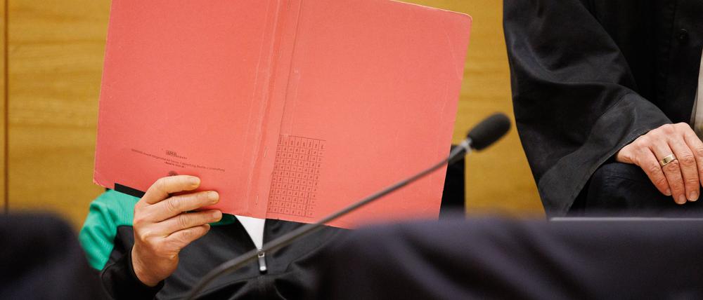 Einer der Angeklagten am Landgericht Bielefeld sitzt neben seinem Verteidiger und verdeckt sein Gesicht.