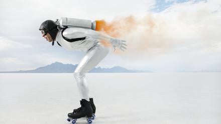 Ein Mann mit Sturzhelm und auf Rollschuhen düst mit einem Triebwerk auf dem Rücken über eine Ebene.