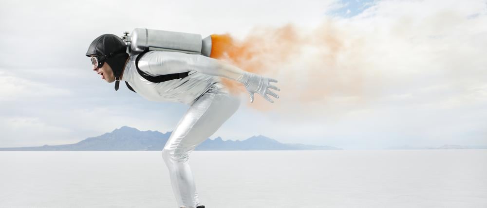 Ein Mann mit Sturzhelm und auf Rollschuhen düst mit einem Triebwerk auf dem Rücken über eine Ebene.