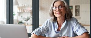 Eine Frau mit grauen Haaren sitzt vor Ihrem Laptop.