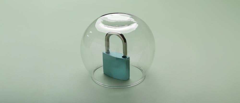 Ein Vorhängeschloss steht unter einer Glaskuppel.