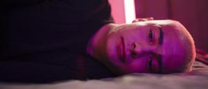 Ein traurig blickender junger Mann liegt seitlich auf einem Bett (Symbolbild).