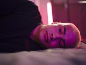 Ein traurig blickender junger Mann liegt seitlich auf einem Bett (Symbolbild).