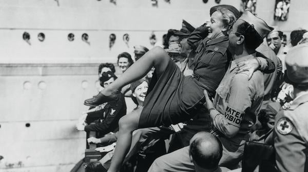 Marlene Dietrich wird von amerikanischen Soldaten auf Händen getragen.