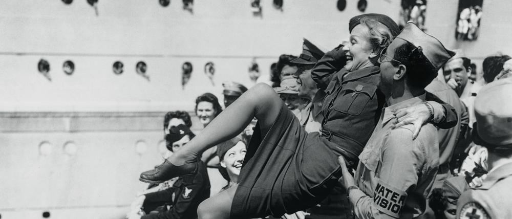 Marlene Dietrich wird von amerikanischen Soldaten auf Händen getragen.