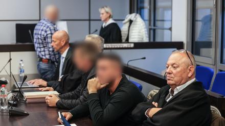 Die drei Angeklagten (hinten l, 2.v.r. und 3.v.r) sitzen zwischen ihren Anwälten Sven Schnitzer (2.v.l.) und Hartmut Moizio (r) im Landgericht Wuppertal.