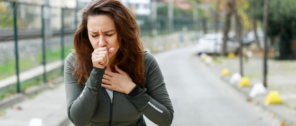 Eine Frau hustet beim Sporttreiben.