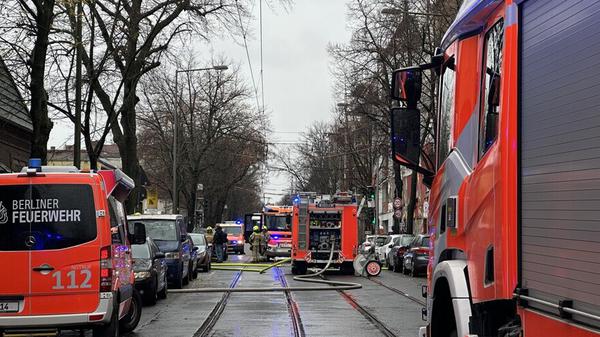 Einsatzkräfte der Berliner Feuerwehr stehen neben Löschfahrzeugen in der Langhansstraße.