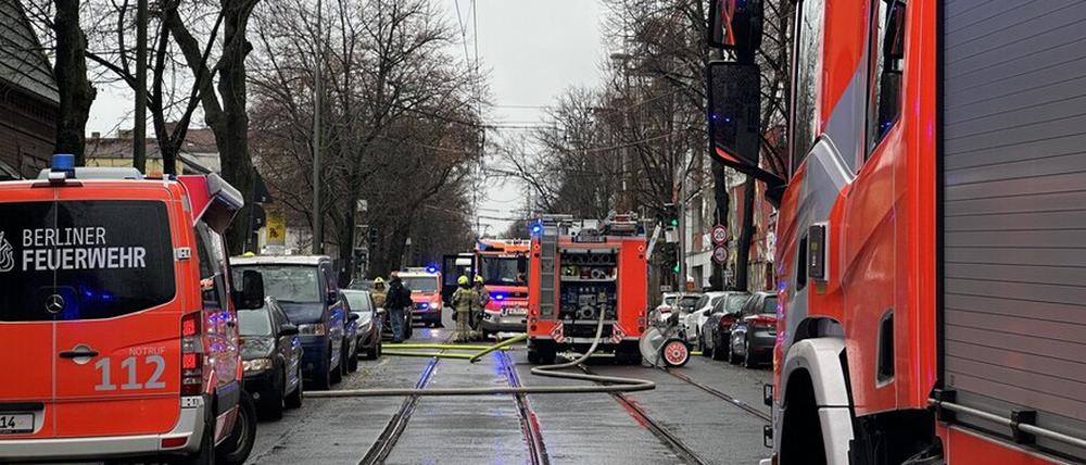 Einsatzkräfte der Berliner Feuerwehr stehen neben Löschfahrzeugen in der Langhansstraße.