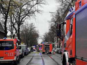 Einsatzkräfte der Berliner Feuerwehr stehen neben Löschfahrzeugen in der Langhansstraße.