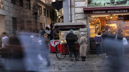 Menschen gehen an einem Imbissstand auf der Istiklal-Straße vorbei, einer belebten Fußgängerzone, die für ihr Street Food und ihren historischen Charme bekannt ist.