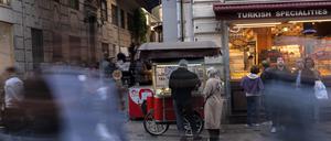 Menschen gehen an einem Imbissstand auf der Istiklal-Straße vorbei, einer belebten Fußgängerzone, die für ihr Street Food und ihren historischen Charme bekannt ist.