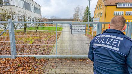 Ein Polizist am Tor zu einem Schulgelände (Symbolbild).