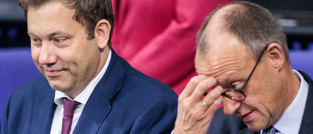 Lars Klingbeil (SPD, l), Bundesminister der Finanzen, und Bundeskanzler Friedrich Merz (CDU) sitzen zu Beginn der Plenarsitzung in der Regierungsbank im Deutschen Bundestag.