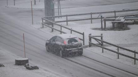 Ein Wagen fährt über eine verschneite Straße im Allgäu.