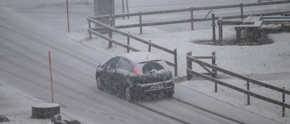 Ein Wagen fährt über eine verschneite Straße im Allgäu.