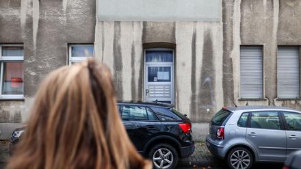 Eine Frau steht vor einem Mehrfamilienhaus. In diesem Mehrfamilienhaus in Bochum ist ein zwölfjähriges Mädchen bei einem Polizeieinsatz durch Schüsse aus einer Dienstwaffe lebensgefährlich verletzt worden.