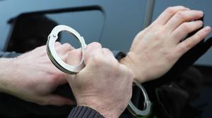 Ein Polizist legt einem Mann Handschellen an. (Symbolbild)