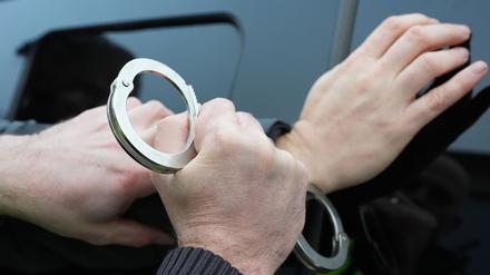 Ein Polizist legt einem Mann Handschellen an. (Symbolbild)