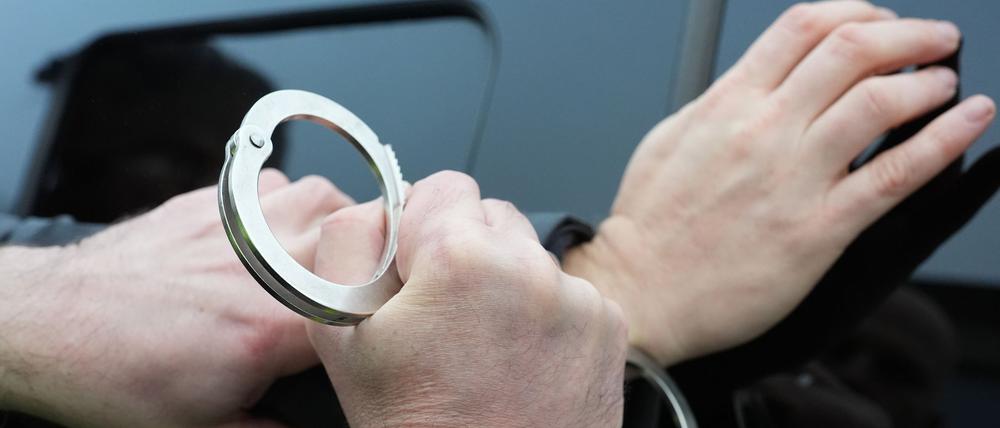 Ein Polizist legt einem Mann Handschellen an. (Symbolbild)