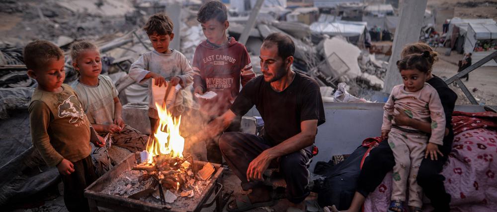 Ein Mann und einige Kinder an einem Feuer inmitten von Trümmern in Gaza.