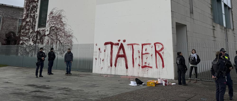 Aktivisten protestieren am 18.11.2025 gegen deutsche Rüstungspolitik, indem sie das Wort ‘Täter’ und rote Handabdrücke an der Wand des Kanzleramts hinterlassen 
