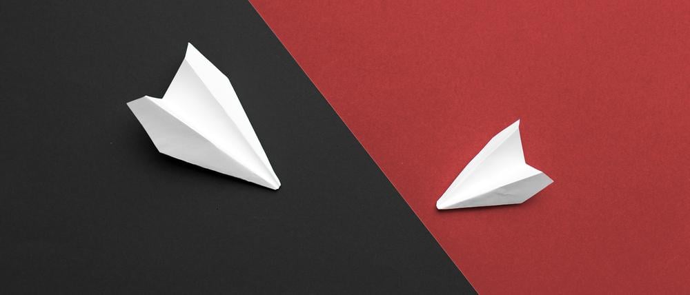 Zwei weiße Papierflieger auf schwarzem und rotem Hintergrund symbolisieren die Uneinigkeit bei SPD und Union.