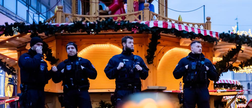 Polizisten sichern den Weihnachtsmarkt in Magdeburg, wobei Kerzen vor ihnen brennen.