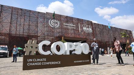 Besucher gehen vor dem Haupteingang der COP30 neben einem großen COP30-Schild auf der UN-Klimakonferenz entlang.