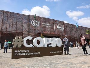 Besucher gehen vor dem Haupteingang der COP30 neben einem großen COP30-Schild auf der UN-Klimakonferenz entlang.