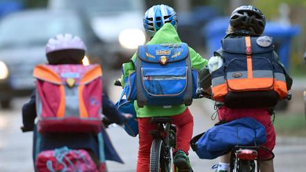 Kinder sind auf einer Straße mit dem Fahrrad unterwegs zur Schule. (Symbolbild)